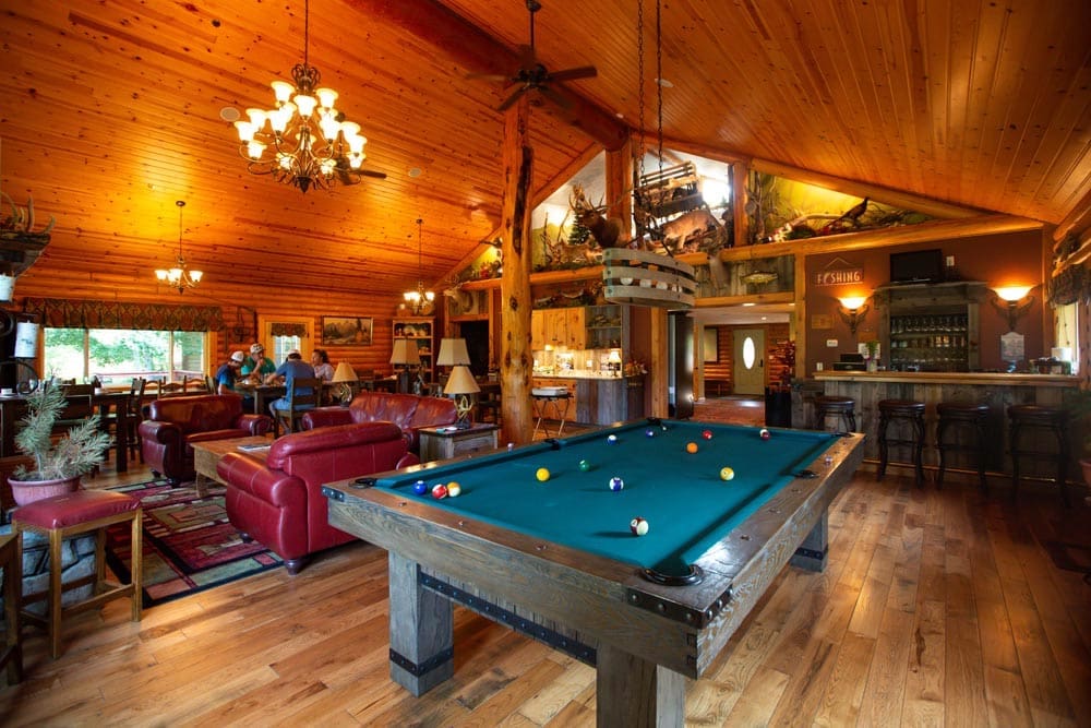 Image of pool table with bar and restaurant tables in background