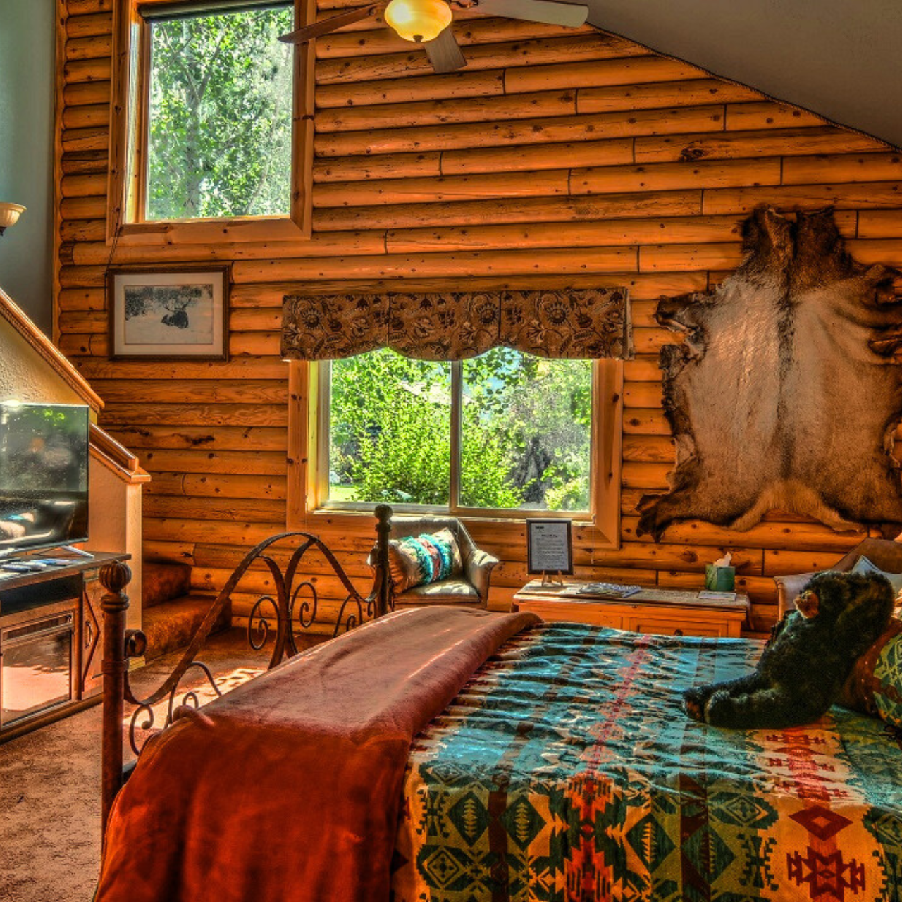 image of queen bed in oversized suite with picture window and staircase at River Retreat Lodge in Swan Valley Idaho