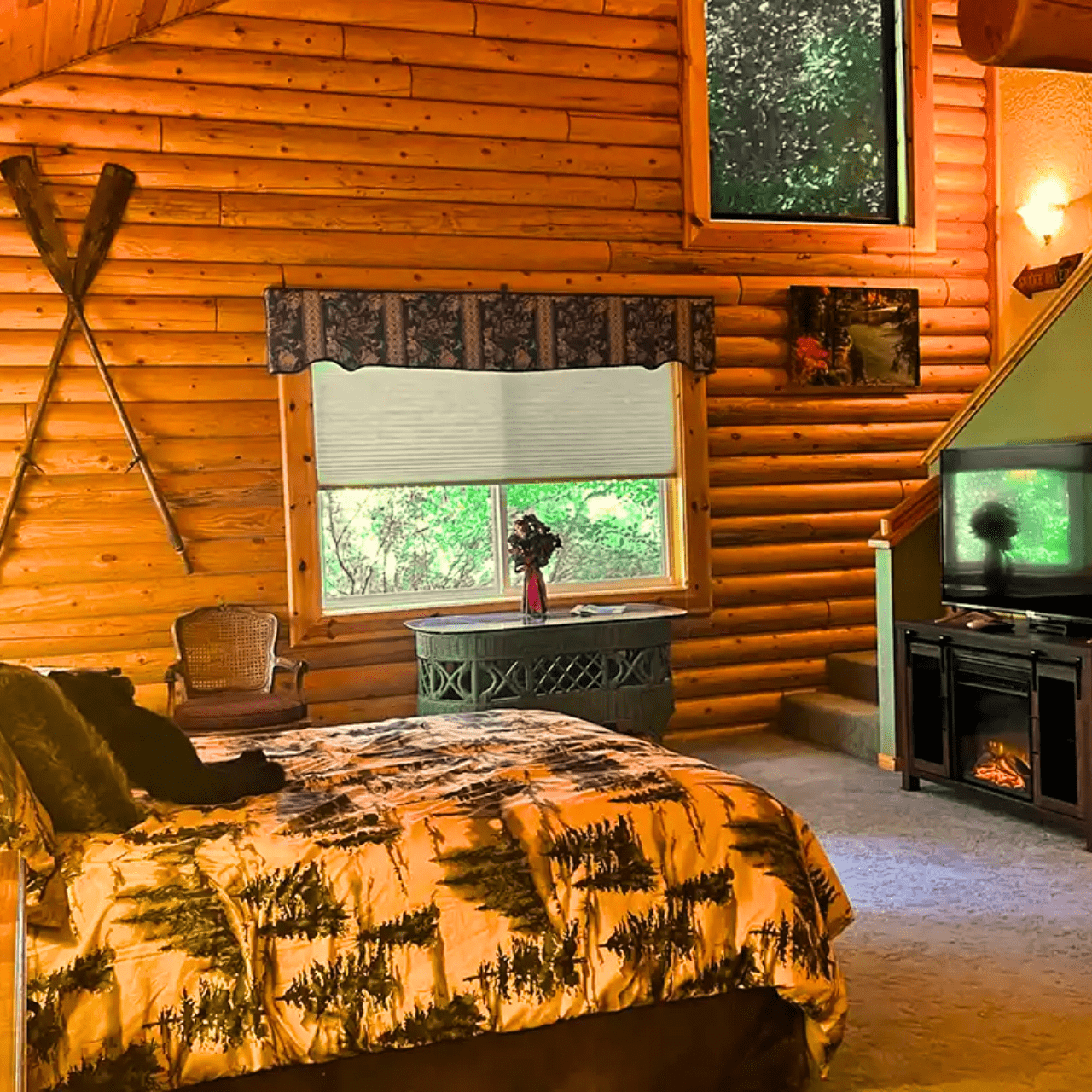 Image of queen bed with stuffed black bear, gas fireplace and tv in oversized suite in Swan Valley